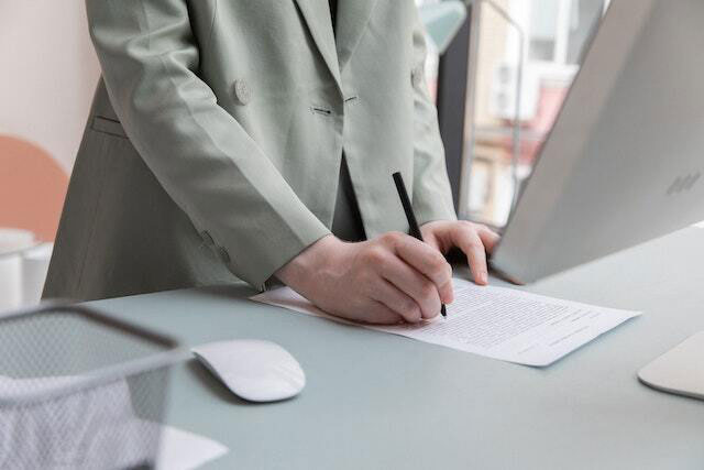 Signing a contract at a desk in front of a computer